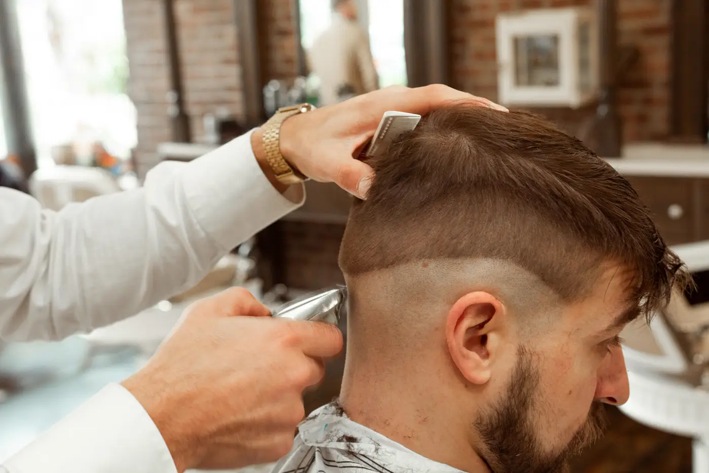 Barbero perfilando un degradado con máquina y peine